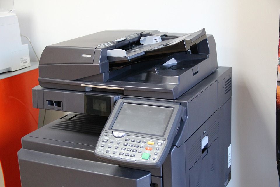 Photocopieur multifonction avec chargeur automatique de documents, posé contre un mur