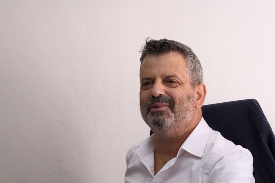 Enseignant assis à son bureau, un stylo et des papiers posés devant lui